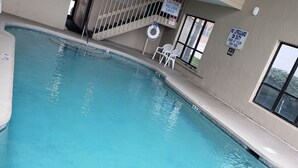 Ein Innenpool mit klarem, blauem Wasser, umgeben von Wänden mit Sicherheitshinweisen und einer Treppe, die zu einer höheren Ebene führt.