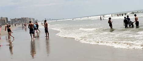 Guests can enjoy a wide beach with gentle waves and scenic views of the surrounding urban area.