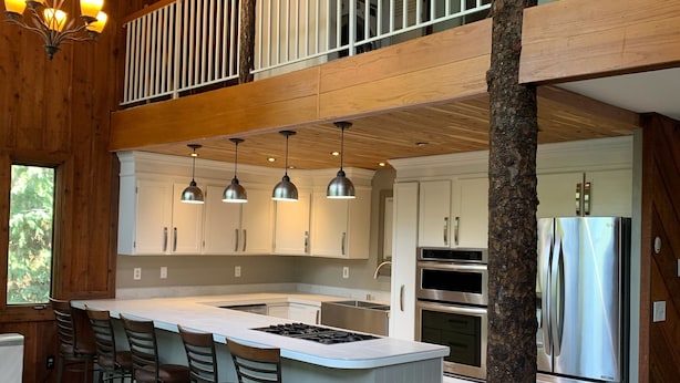 A spacious kitchen with a central island, bar stools, and modern appliances. - Stellar Blue Chalet - Sleeps 6+. Pets on approval. Near Alyeska Ski Resort (Girdwood)