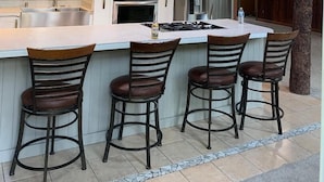 A modern kitchen with a central island, bar stools, and a view of the upper level. - Stellar Blue Chalet - Sleeps 6+. Pets on approval. Near Alyeska Ski Resort (Girdwood)