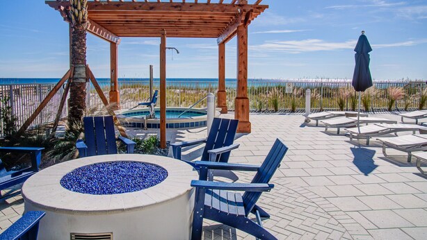 Eine Terrasse direkt am Strand mit einer Holzpergola, Liegestühlen, einem Whirlpool und Blick auf den Ozean.