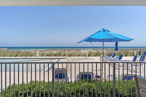 A poolside area with lounge chairs and a blue umbrella, overlooking the beach. - Blu 107 ~ Oceanfront 4BR/3BA ~ Sleeps 10 ~ Ground Floor End Unit! (Fort Walton Beach)