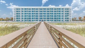 Ein modernes Hotel mit langer Holzpromenade, die zu einem mehrstöckigen Gebäude mit Balkonen führt.