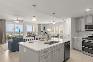 A modern kitchen with a central island, stainless steel appliances, and a view to the outside. - Blu 107 ~ Oceanfront 4BR/3BA ~ Sleeps 10 ~ Ground Floor End Unit! (Fort Walton Beach)
