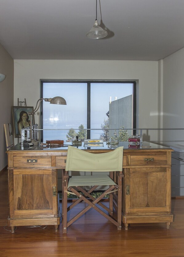 Un escritorio de madera con una silla, una lámpara y una ventana que ofrece vistas a edificios.