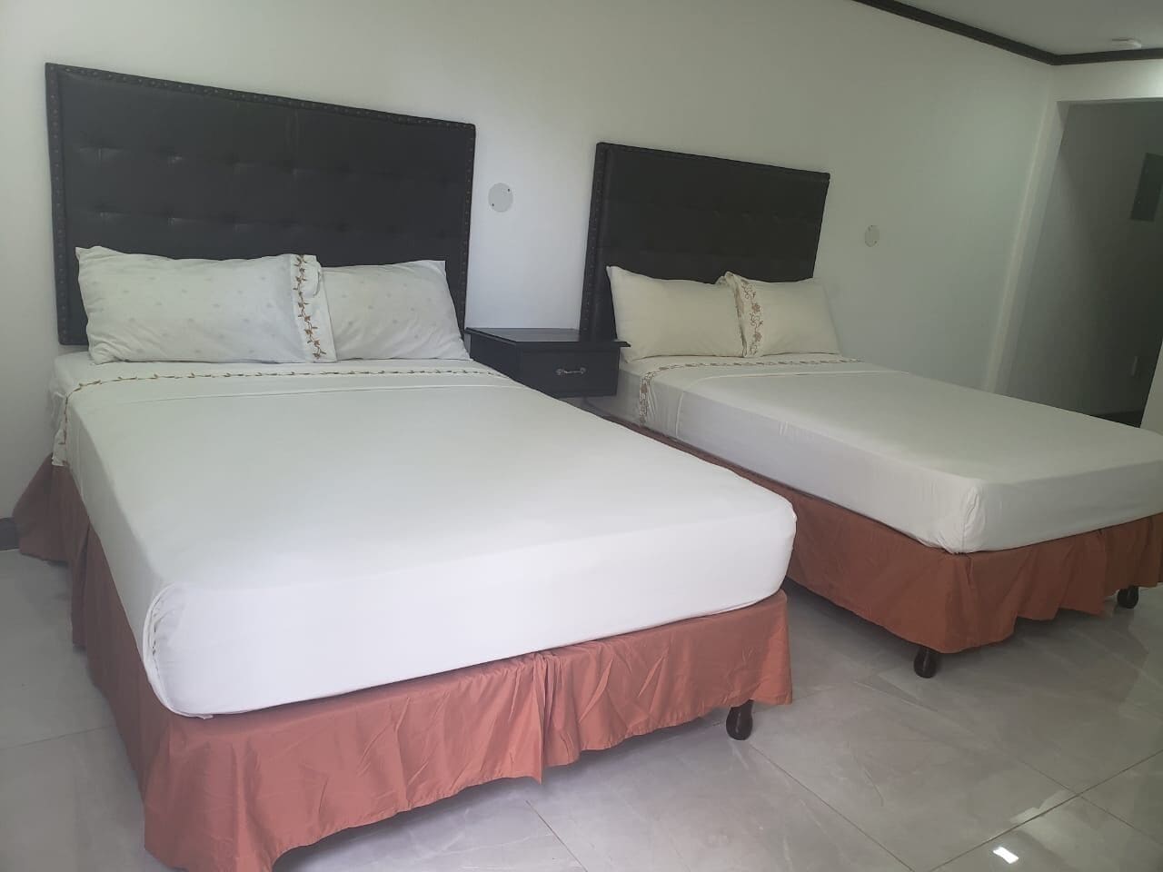 Two single beds with headboards, a nightstand, and a wall-mounted TV.