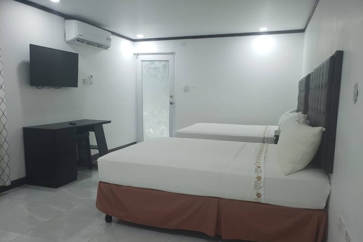 A bedroom with two beds, a desk, and a TV.