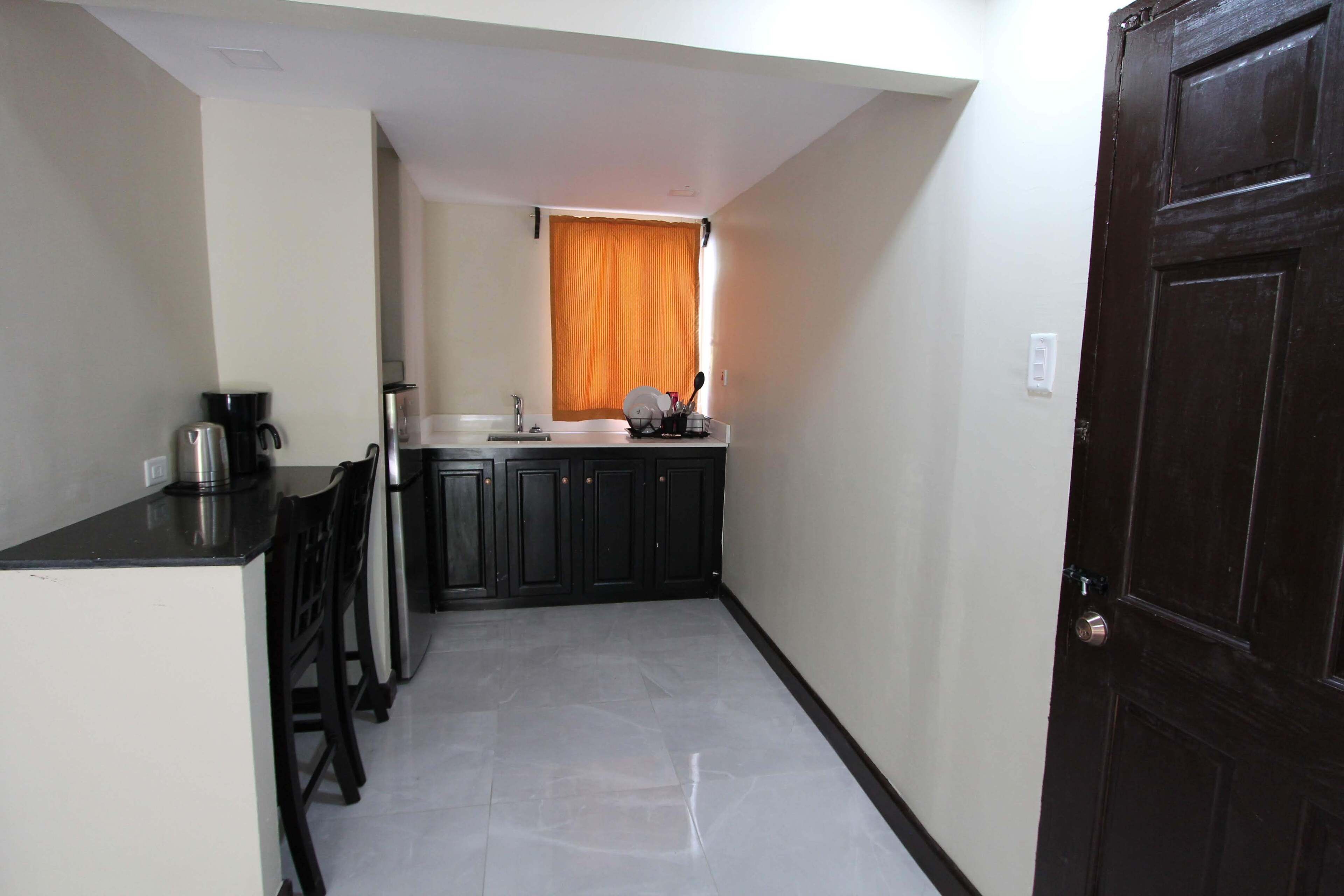 A compact kitchen with a dark countertop, a coffee maker, and a sink.