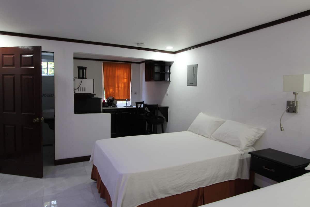 A hotel room with a bed, a desk, a chair, and a wardrobe.