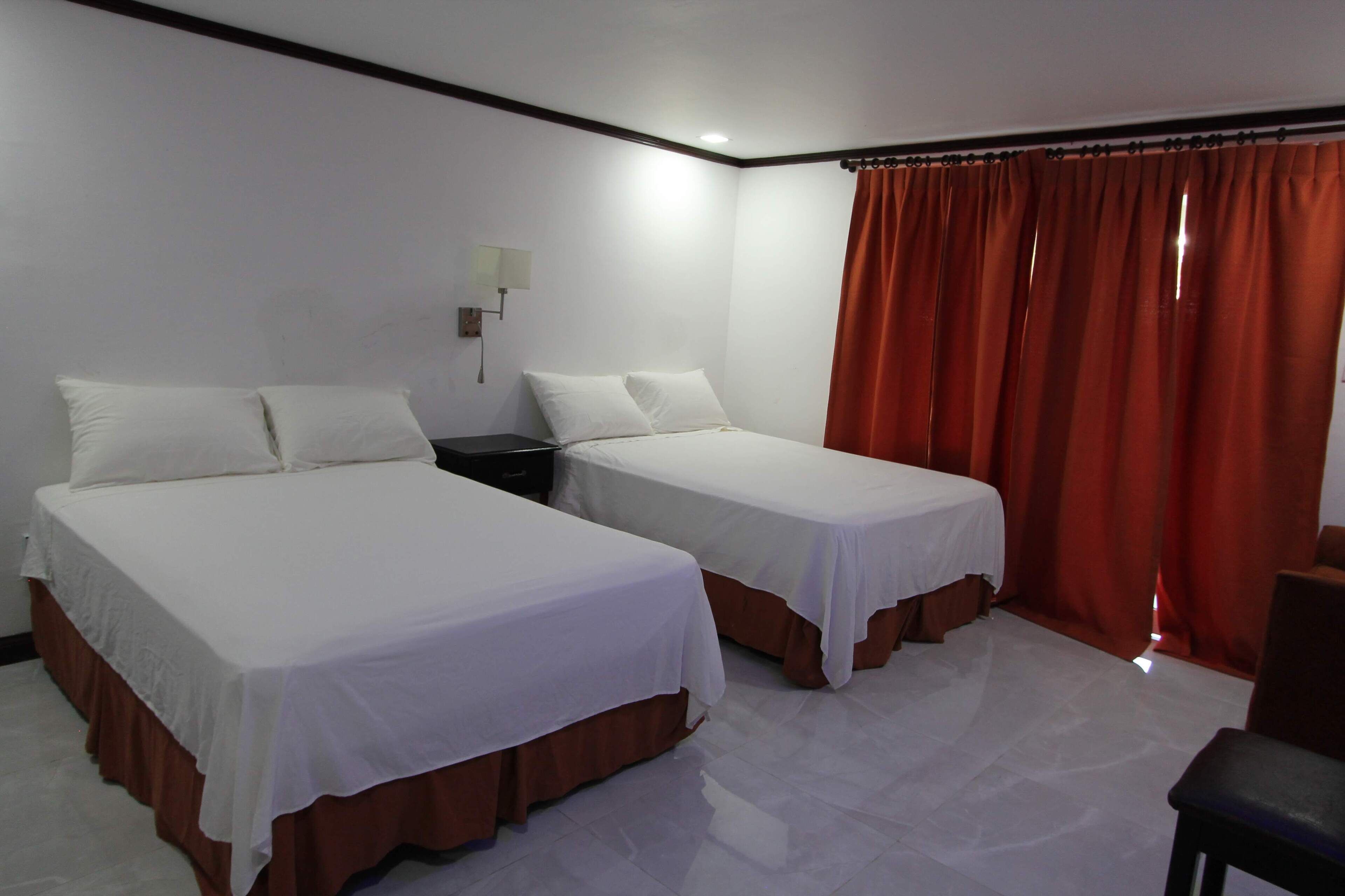 A hotel room with two single beds, a nightstand, a desk, and a chair.