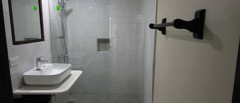 A bathroom with a white sink, a glass shower enclosure, and a mirror.