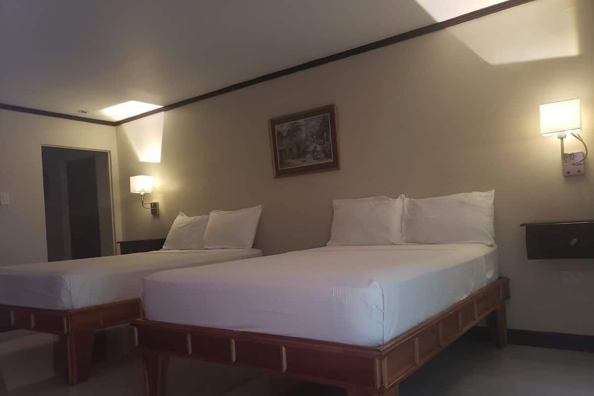 A hotel room with two single beds, a nightstand, a lamp, and a painting on the wall.