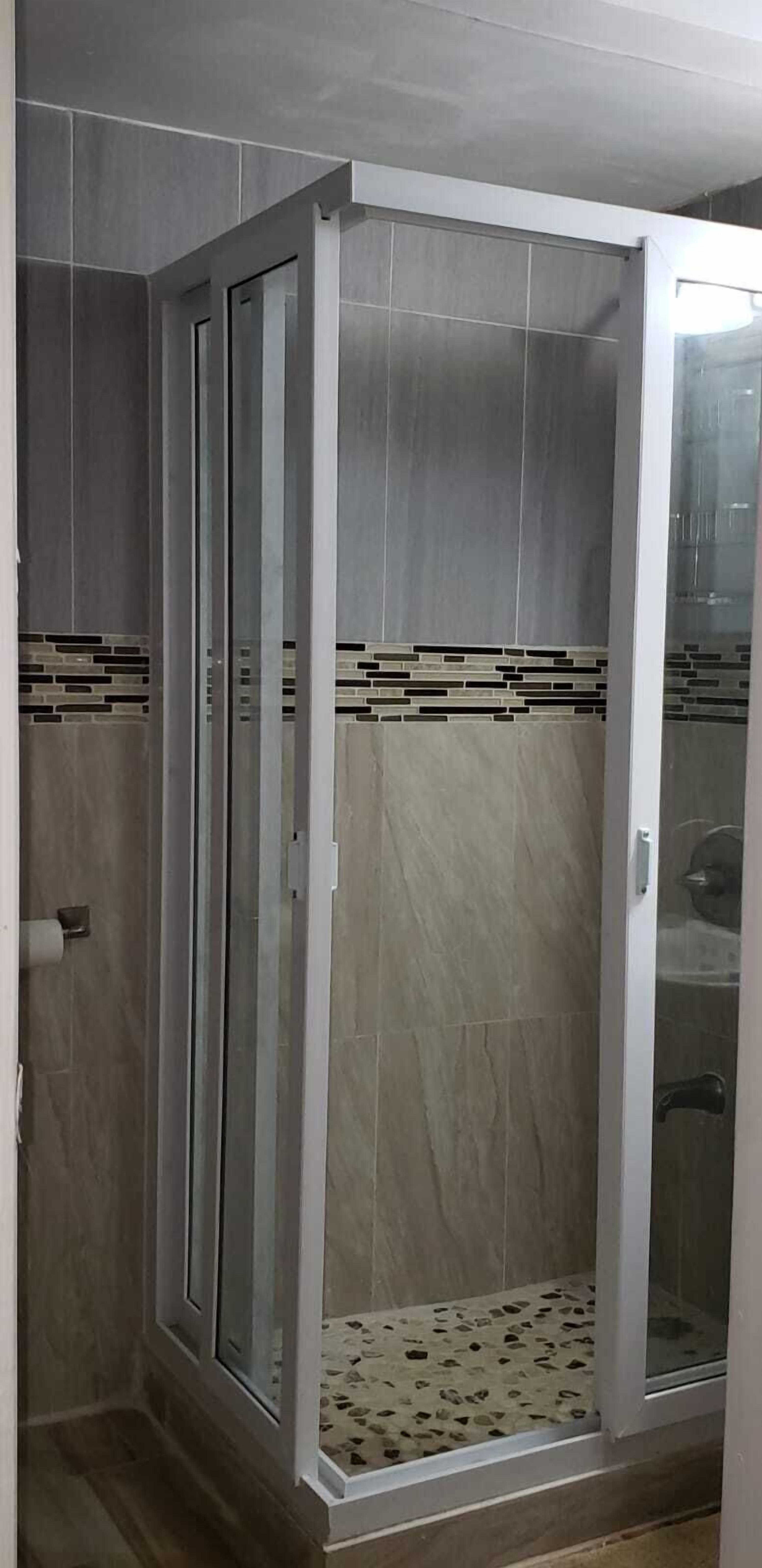 A walk-in shower with a glass door, tiled walls, and a patterned floor.