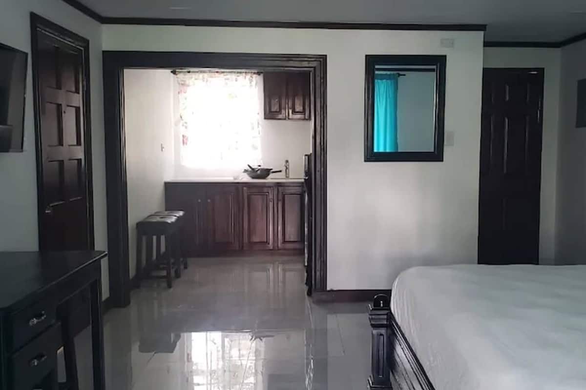 A hotel room with a bed, a desk, a chair, a wardrobe, and a bathroom visible through an open door.