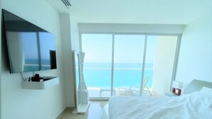 A modern hotel room with a large bed, a flat-screen TV mounted on the wall, and a large window offering a view of the sea. - Haytt-h2 Bocagrande Cartagena condominium (Cartagena)