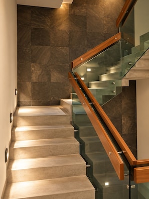 Eine moderne Treppe mit Glastrennfeldern und Holzhandläufen, die zu einer Ebene weiter unten führt.