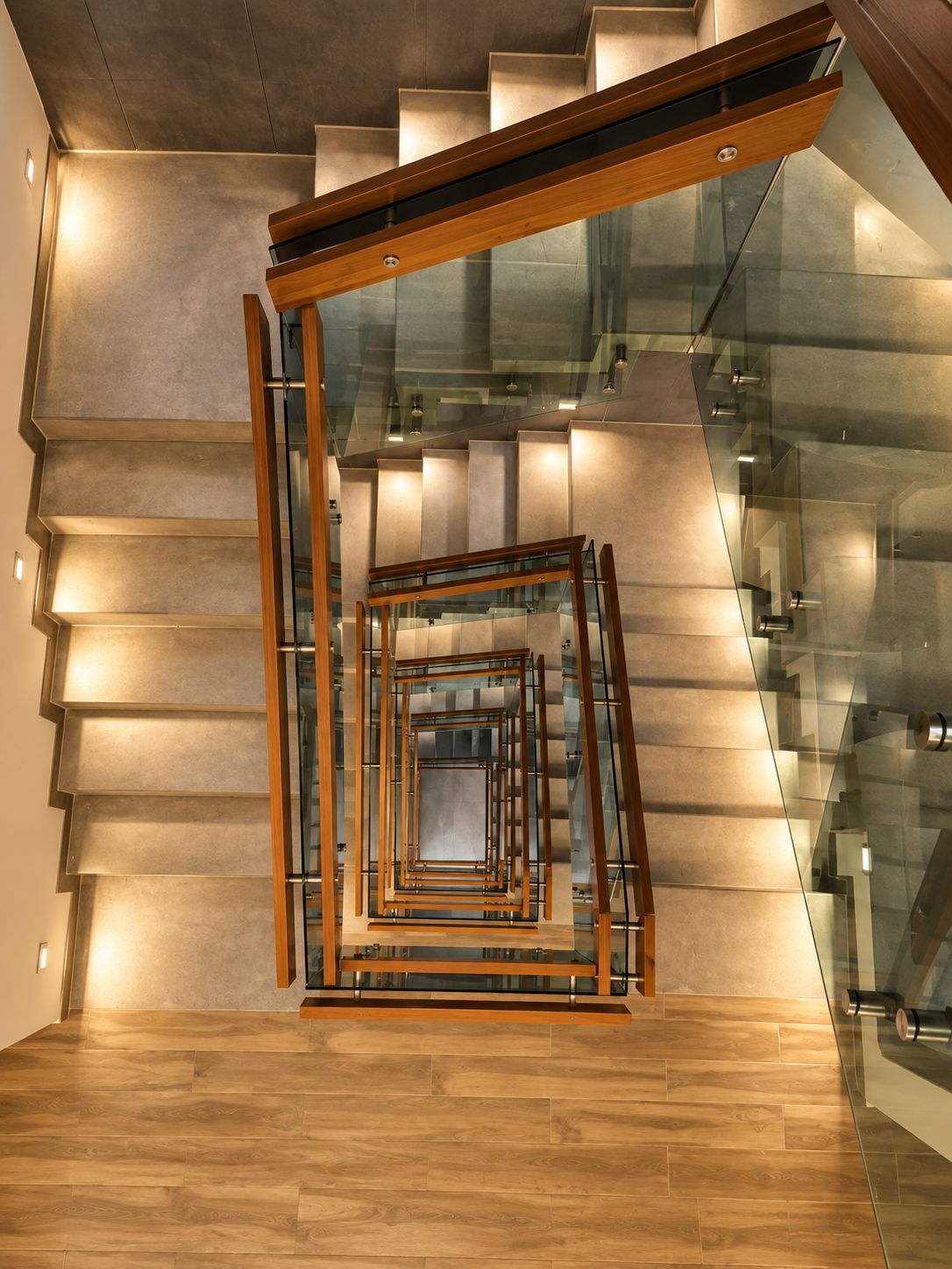 Eine moderne Treppe mit Glastrennwand und Holzhandläufen.