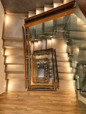 Un escalier moderne avec des rampes en verre et des mains courantes en bois.