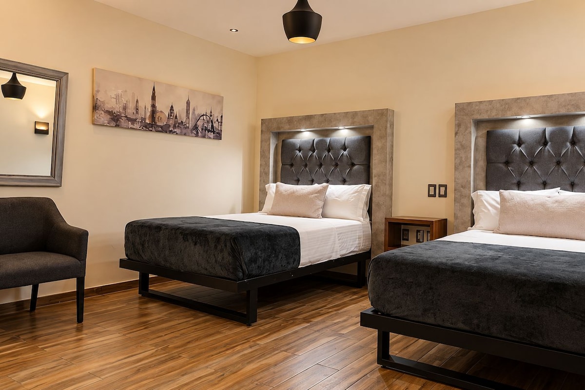 Une chambre d’hôtel avec deux lits, une chaise et un tableau au mur.