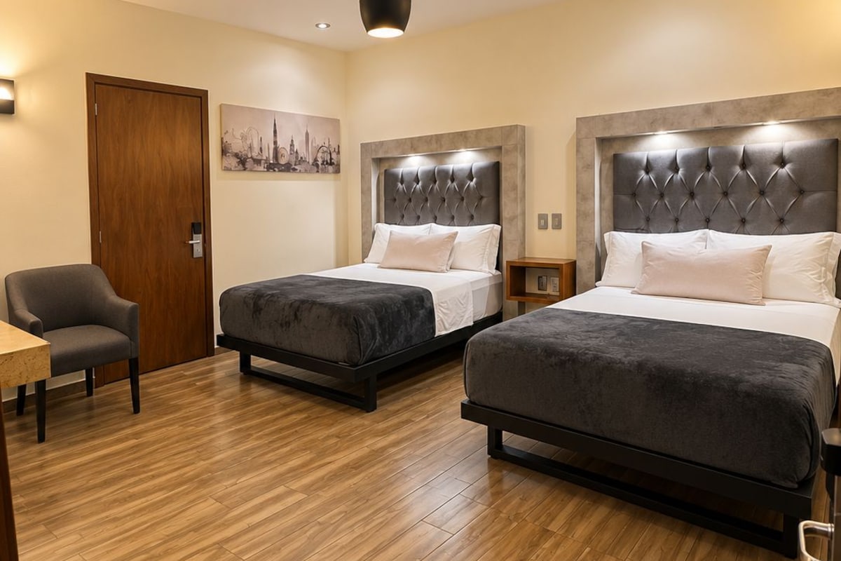 Une chambre d’hôtel avec deux lits, un plancher en bois, une chaise et un tableau accroché au mur.