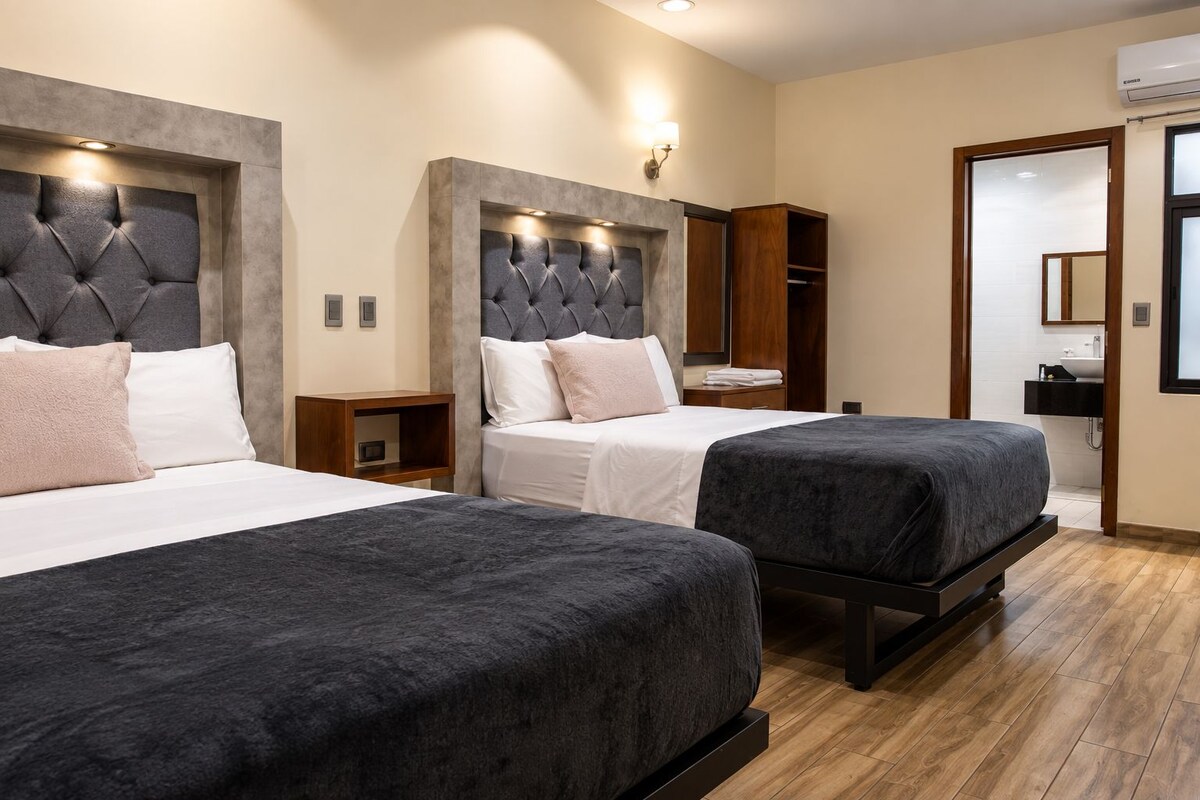 Une chambre d’hôtel avec deux lits, une armoire, une coiffeuse et un miroir.
