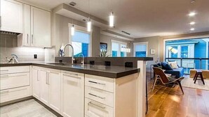 Une cuisine moderne avec des meubles blancs, un îlot central et des luminaires suspendus.