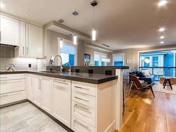 A modern kitchen with white cabinetry, a central island, and pendant lighting. - Walk to Main St. & Town Lift – New Old Town Home w/ Hot Tub (Park City)