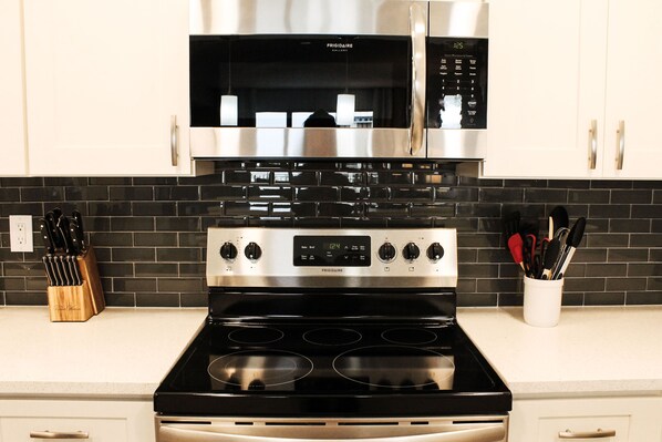 Enjoy cooking in this well-equipped kitchen with a digital oven and microwave, a knife block, and utensil holder.