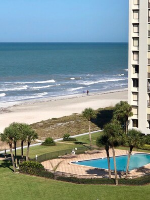 Enjoy ocean views from the comfort of your balcony, surrounded by palm trees and a sandy beach.