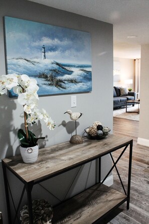 Relax in a serene space with a stunning lighthouse painting, a potted orchid, and a decorative bird sculpture.