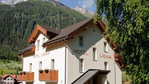 A two-story hotel with balconies and a mountain backdrop. - Hotel Ladina (Berguen)
