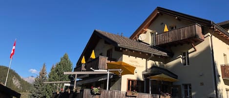 Un edificio de dos pisos con balcones, barandillas de madera y un letrero que indica que es un hotel y restaurante.