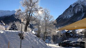A snow-covered mountain landscape with a parking area, buildings, and a lamp post. - Hotel Ladina (Berguen)