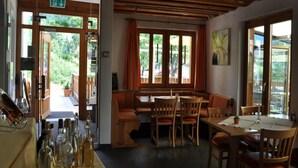 A restaurant with wooden furniture, a bench, and a table with bottles. - Hotel Ladina (Berguen)