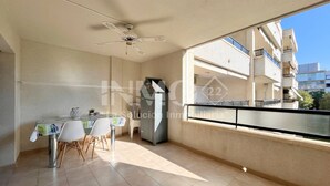 A balcony with a view of a building, a ceiling fan, and a table with chairs. - Regata green areas with swimming pools  (Cambrils)