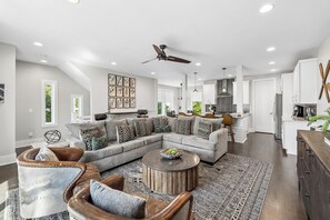 Un salon moderne avec un canapé d’angle, une table basse ronde et un ventilateur de plafond.