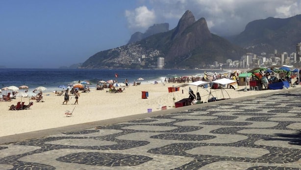A beach with a patterned pavement, umbrellas, and people. - Ipanema (Rio de Janeiro)
