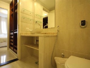 Un baño con lavamanos blanco, repisas de vidrio, un espejo y un inodoro.