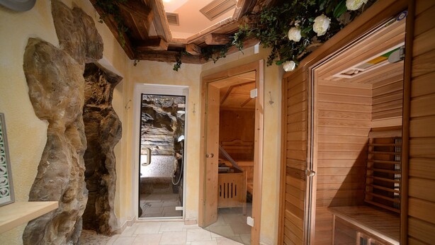 A hallway with a stone wall, wooden door, and a wooden bench. - Hotel Compet (Vignola-Falesina)
