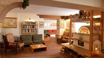 Ein gemütliches Wohnzimmer mit Kamin, Bücherregalen, einer Couch und einem Holztisch.