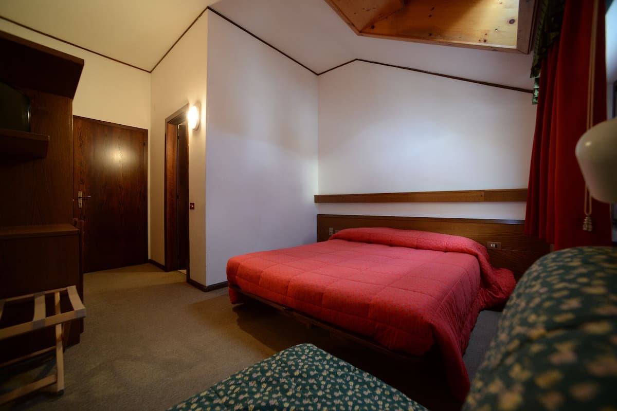 Ein Schlafzimmer mit einem hölzernen Bett, einem Holzschrank und einer kleinen Bank.