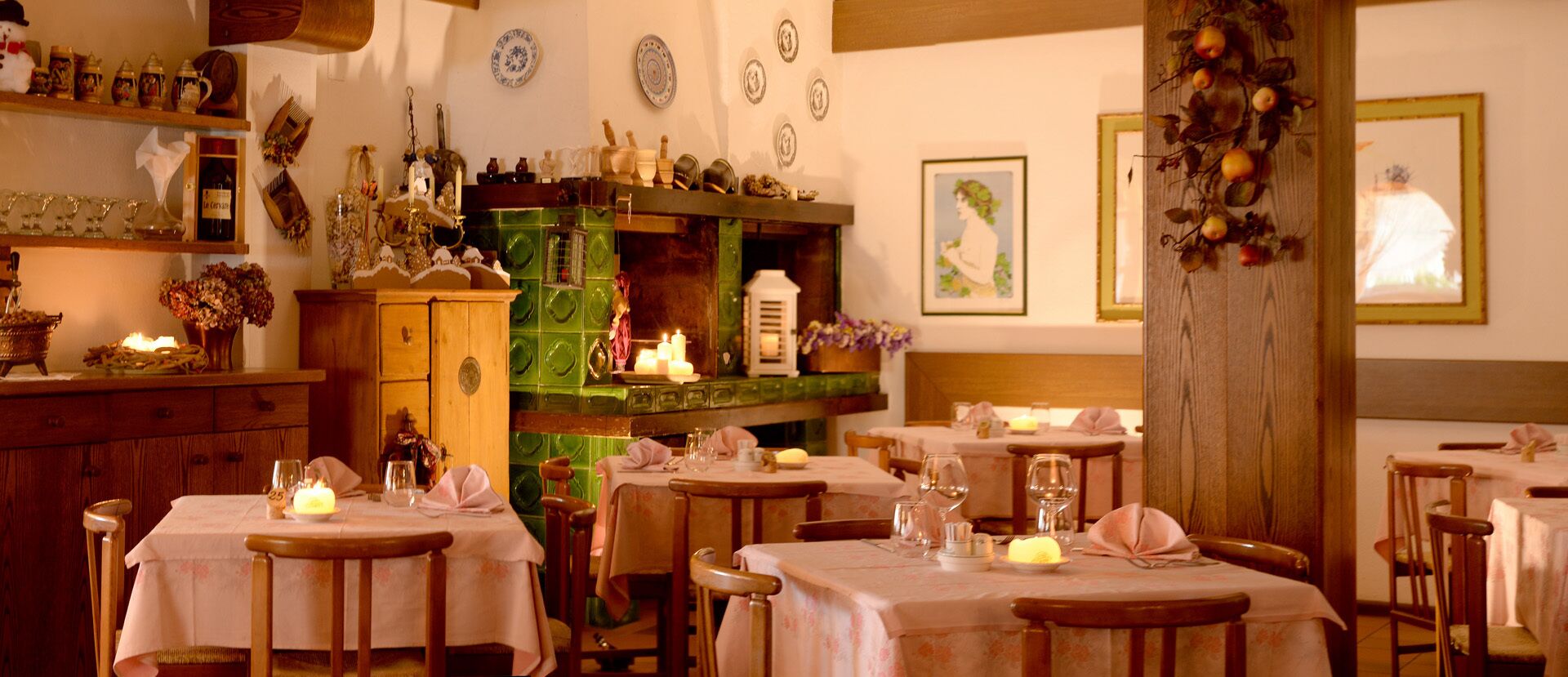 A cozy dining area with multiple tables set for guests, featuring wooden chairs and tables covered with white tablecloths.