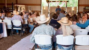 An indoor event with attendees seated in rows of white chairs facing a stage. - Country Aire Bed & Breakfast (Rock Spring)