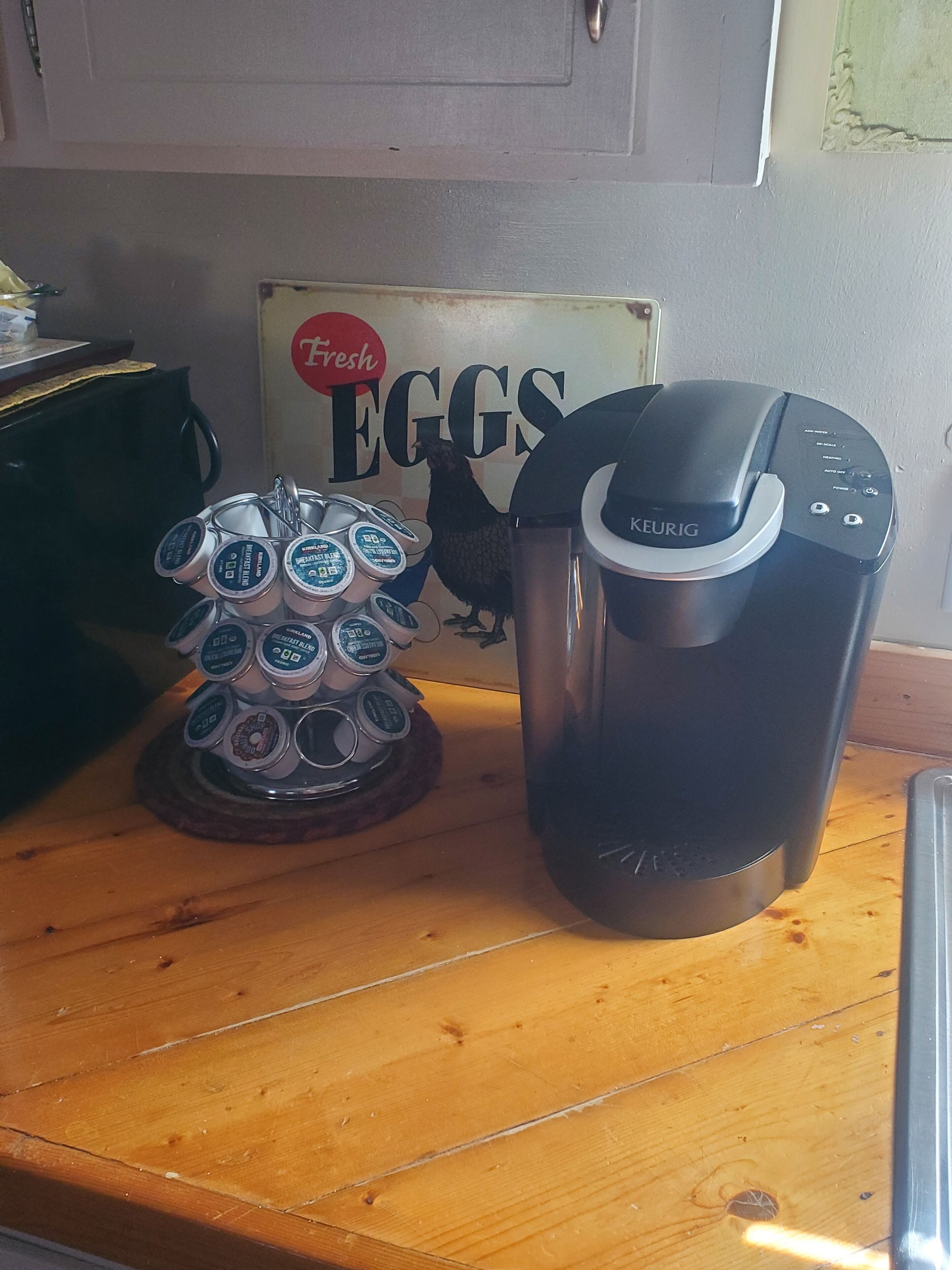 Una encimera de cocina con una cafetera Keurig y un dispensador de cápsulas de café.