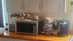 A kitchen with a microwave, toaster, coffee maker, and a clock. - Country Aire Bed & Breakfast (Rock Spring)