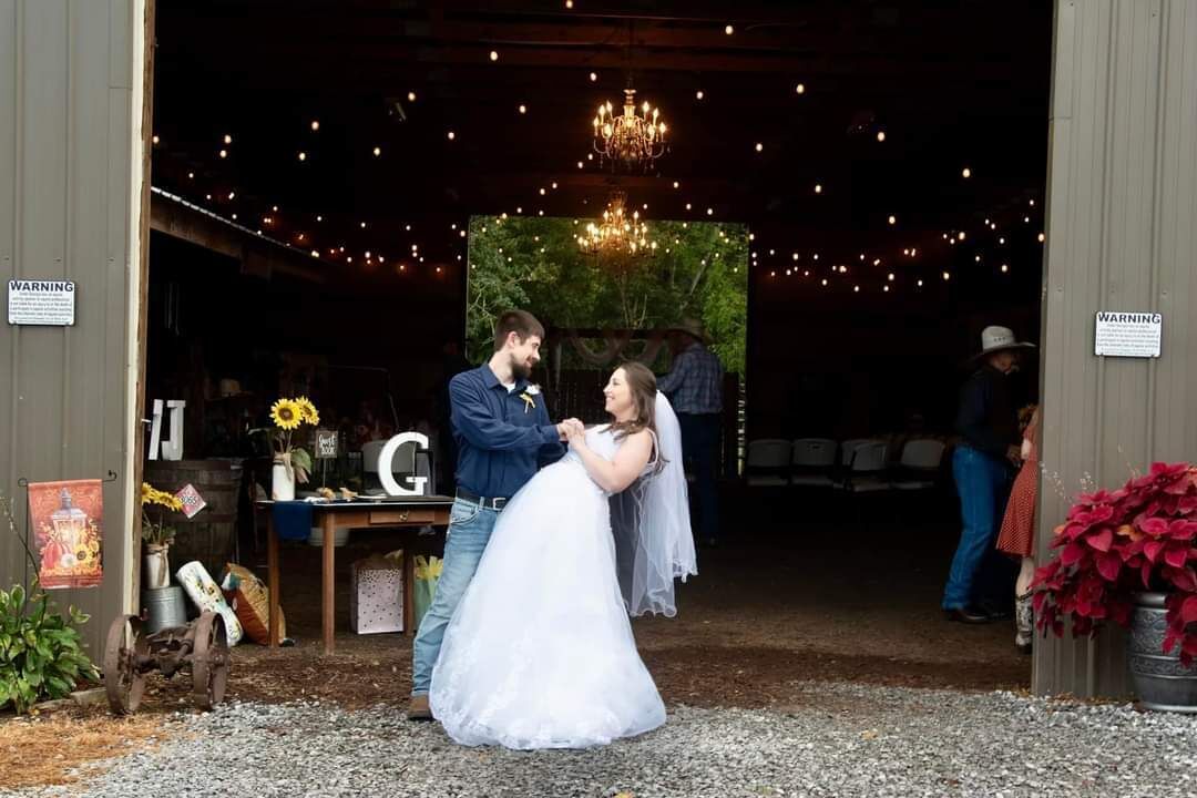 Una ceremonia de boda en un granero rústico con una araña y luces colgantes.