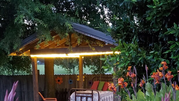 A garden with a wooden pergola, a bed, and various flowers. - Country Aire Bed & Breakfast (Rock Spring)
