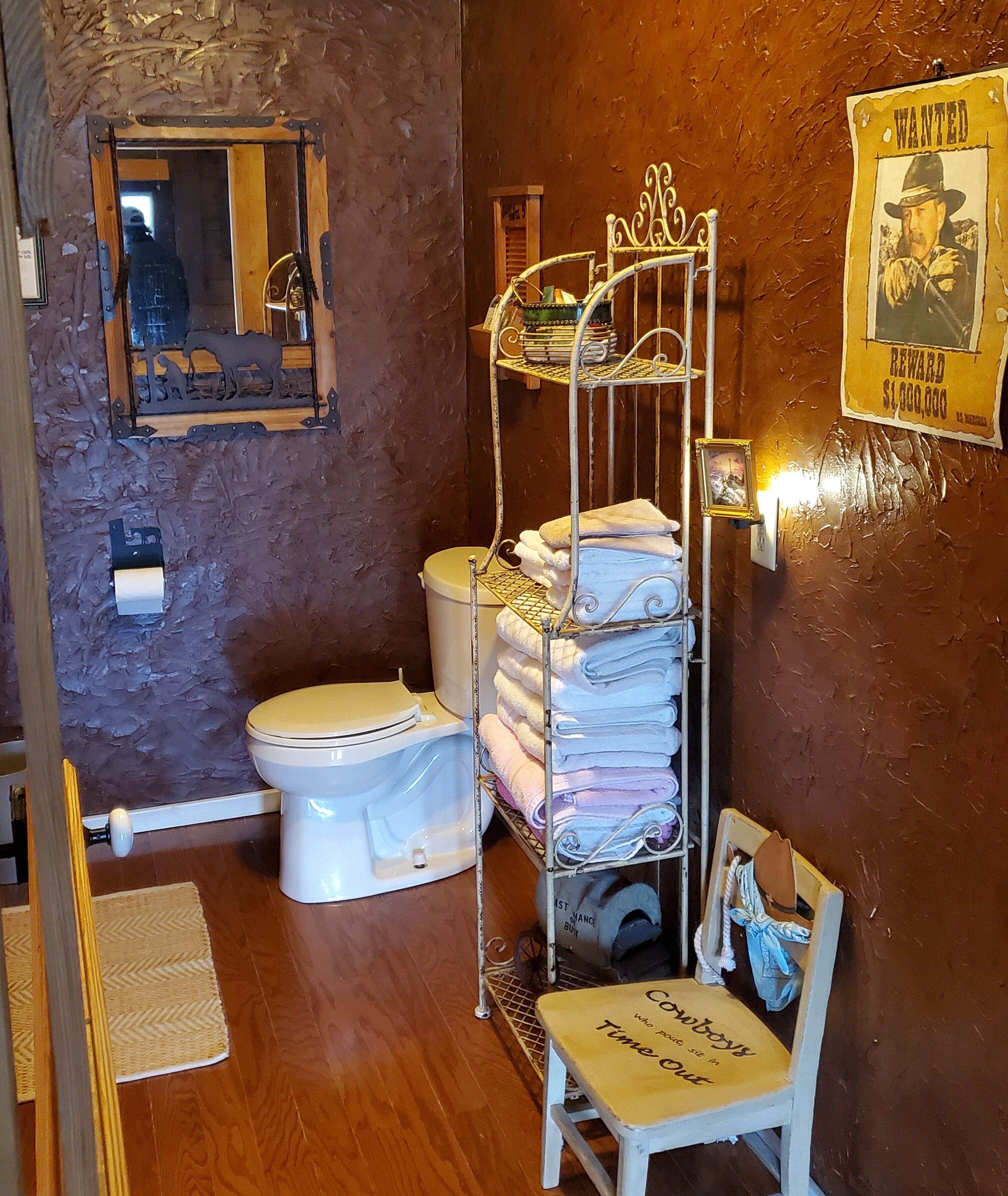 Une salle de bain au style rustique, avec un mur en bois, des toilettes blanches, un porte-serviettes en métal et une affiche « Recherche ».