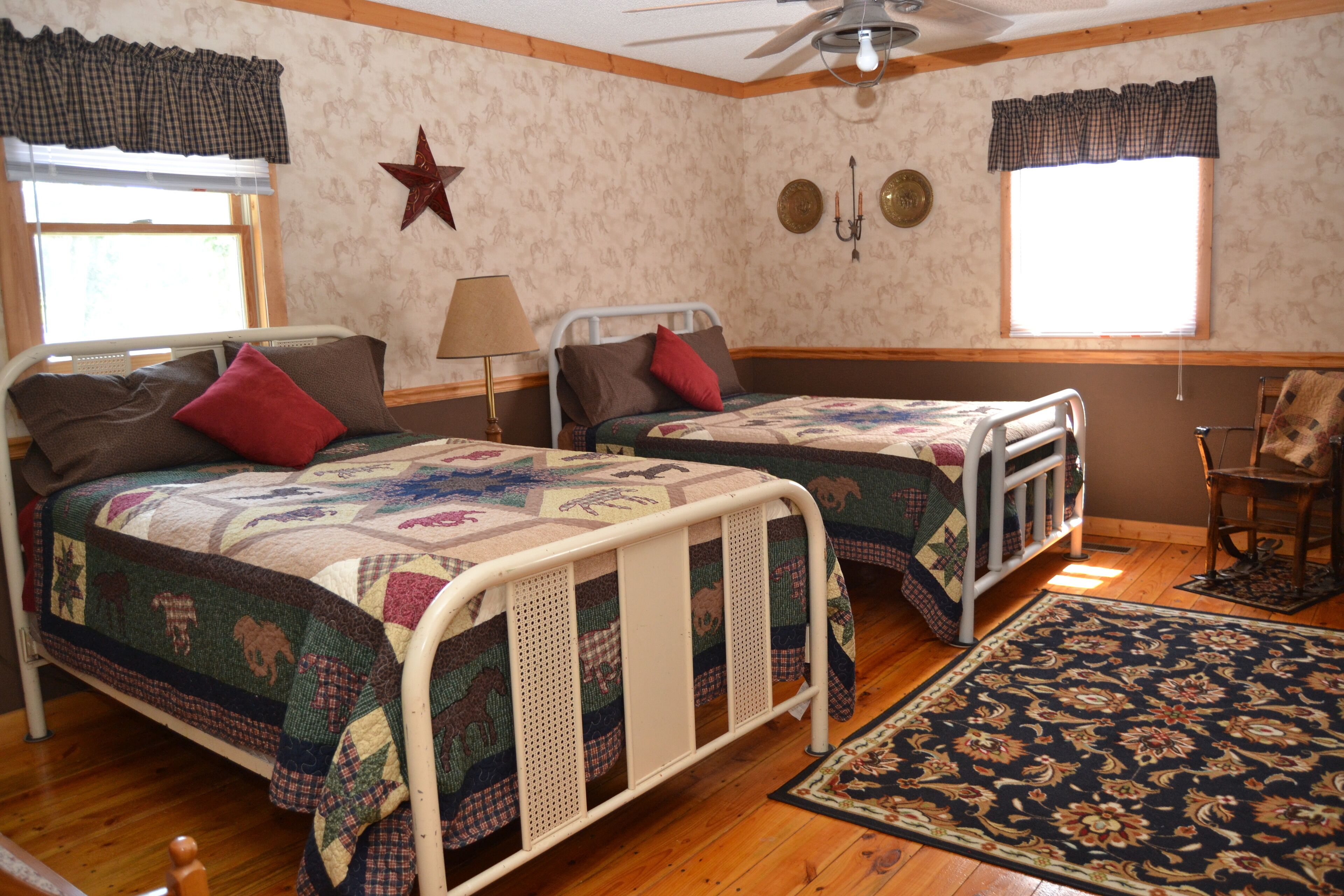 Una habitación con dos camas individuales, suelo de madera, decoración de estrellas y una ventana con cortinas.