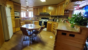 A kitchen with wooden cabinets, a dining table with chairs, a refrigerator, a microwave, a stove, and a sink. -  On Salmon River, quiet, private, house, where you can still see the milky way, (Salmon)